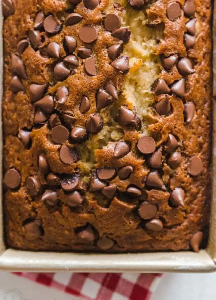 Slice of chocolate chip banana bread on a wooden plate