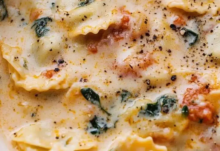 Bowl of creamy Tuscan Ravioli Soup garnished with herbs