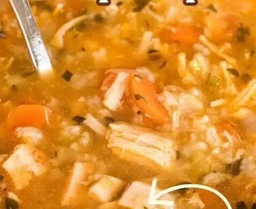 Bowl of homemade rotisserie chicken and rice soup garnished with herbs