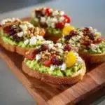 Avocado toast topped with feta, cherry tomatoes, cranberries, and walnuts