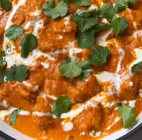 Delicious butter chicken served with rice and garnished with fresh cilantro