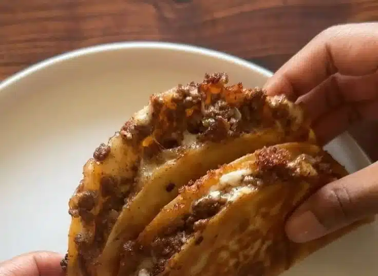 Crispy ground beef tacos topped with fresh ingredients on a plate