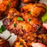 Baked chicken wings on a white platter garnished with herbs