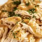 Delicious crockpot chicken and gravy served on a plate.