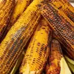 Deliciously grilled corn on the cob, garnished with herbs and spices.