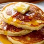 Old-fashioned pancakes stacked and topped with syrup and berries